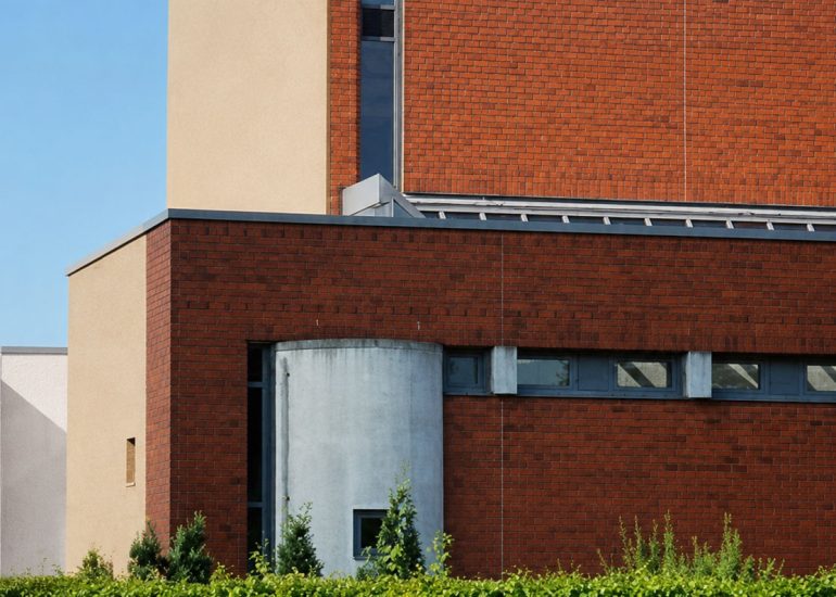 Ecumenical Church exterior with red brick walls, clerestory windows, curved concrete bay, and hedges