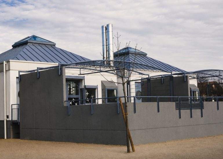 Elementary School Schwetzingen exterior with angular metal roofs, curved trellises, and twin cylindrical flues